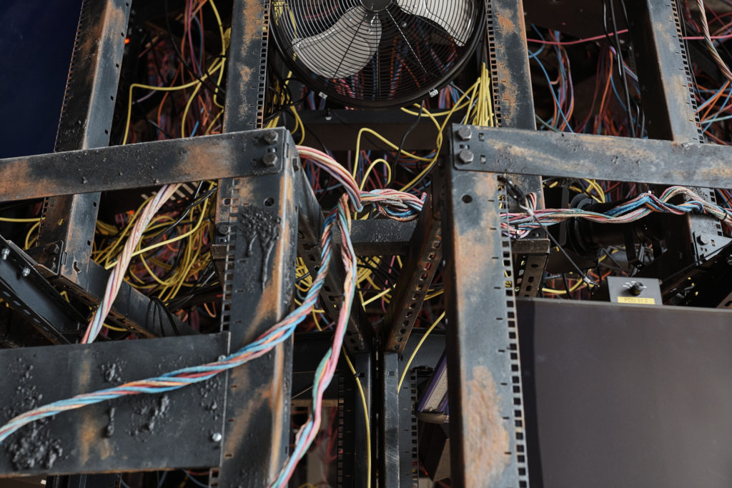 Close up photo of the Entanglement installation by ANNEX at the Venice Architecture Biennale 2021. It shows steel frames filled and entwined by a mass of brightly coloured wires. Part of an old desk fan is visible top centre.