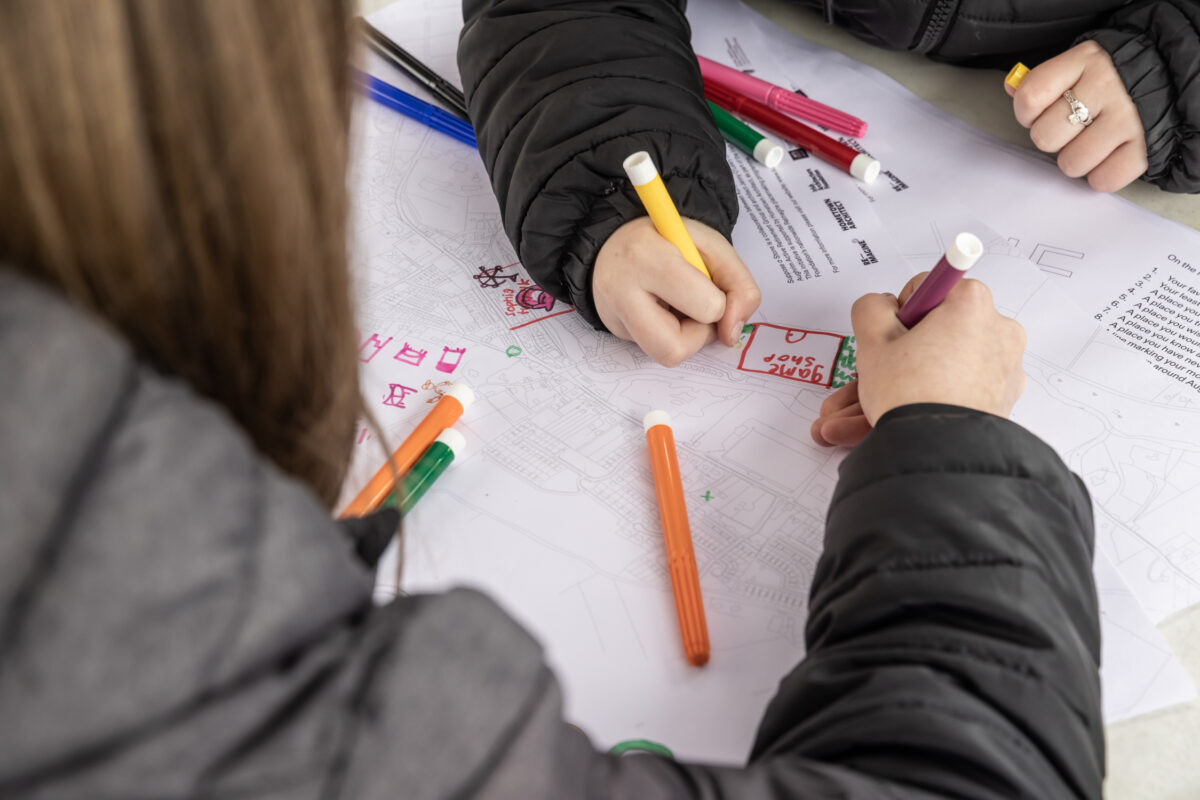 Close up of young people's hands drawing with coloured markers.